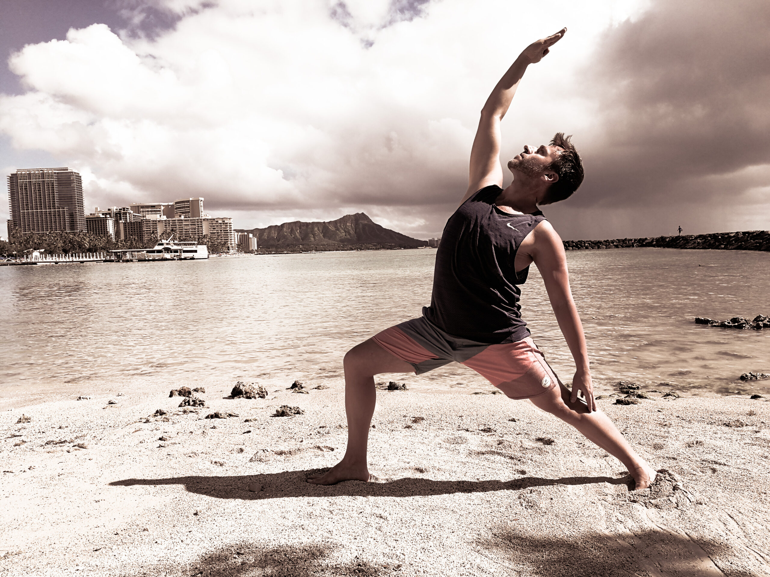 Seb Fit N Yog pratiquant la posture du guerrier du soleil sur la plage de Waikiki Hawaii